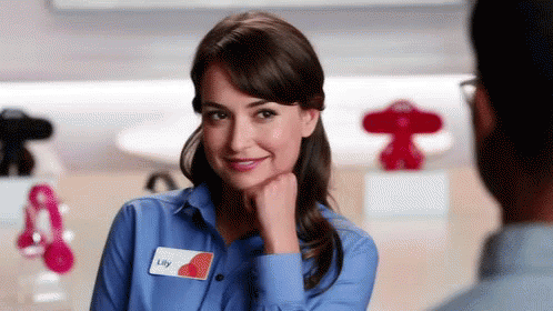 A Woman Wearing A Blue Shirt With A Name Tag That Says Lily GIF