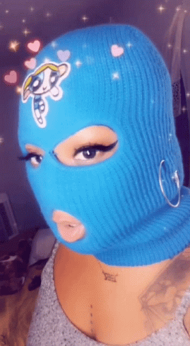 A Woman Wearing A Blue Ski Mask With A Cartoon Character On It . GIF