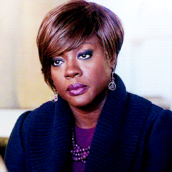 A Woman Wearing A Blue Sweater And Earrings Looks Serious GIF