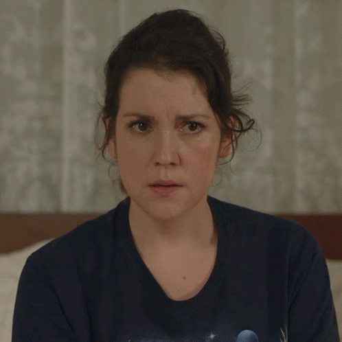 a woman wearing a blue t-shirt with a planet on it looks at the camera