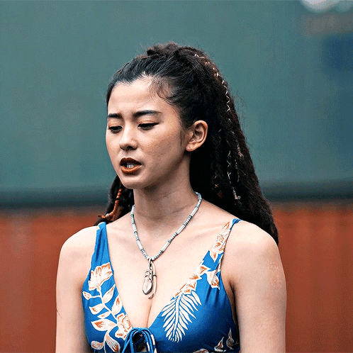 A Woman Wearing A Blue Top And A Necklace With A Leaf On It GIF