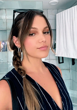 A Woman Wearing A Braided Ponytail Is Taking A Selfie In A Bathroom GIF