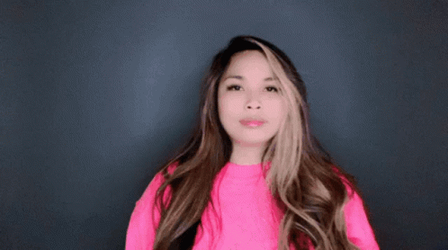 A Woman Wearing A Bright Pink Sweater Is Making A Funny Face GIF