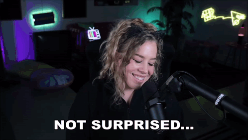 a woman wearing a cat ear headband is talking into a microphone and says not surprised