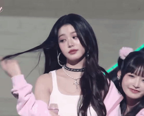 A Woman Wearing A Choker And Hoop Earrings Is Standing Next To Another Girl GIF