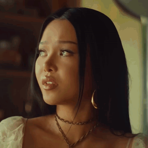 A Woman Wearing A Choker And Hoop Earrings Looks To Her Left GIF