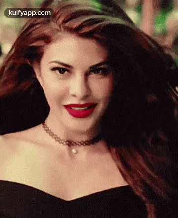 A Woman Wearing A Choker And Red Lipstick Is Smiling . GIF
