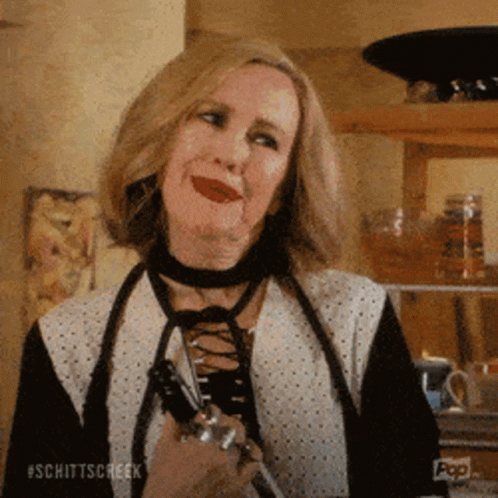 A Woman Wearing A Choker Is Holding A Pair Of Scissors And Smiling . GIF