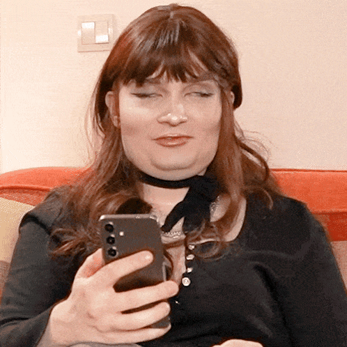 A Woman Wearing A Choker Is Looking At Her Phone GIF