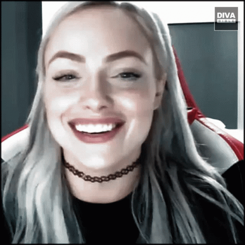 A Woman Wearing A Choker Is Smiling In Front Of A Diva Banner GIF