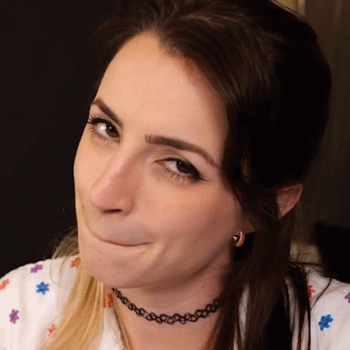 A Woman Wearing A Choker Necklace And Earrings Makes A Funny Face GIF