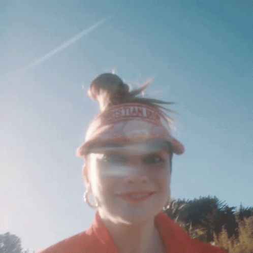 A Woman Wearing A Christian Dior Visor Stands In Front Of A Blue Sky GIF