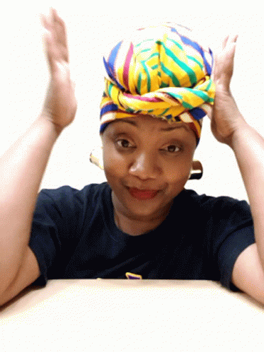 A Woman Wearing A Colorful Head Scarf And A Black Shirt With The Letter T On It GIF