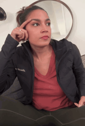 A Woman Wearing A Columbia Jacket Holds Her Finger To Her Eyebrow GIF