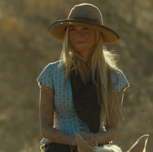 A Woman Wearing A Cowboy Hat And A Blue Shirt Is Riding A Horse GIF