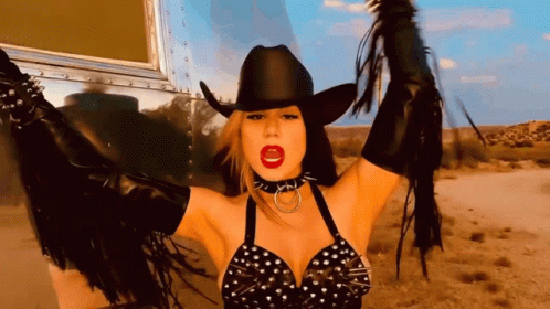 A Woman Wearing A Cowboy Hat And Fringe Gloves GIF