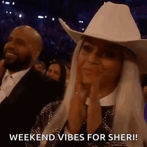 A Woman Wearing A Cowboy Hat Is Clapping Her Hands In A Crowd At A Concert . GIF