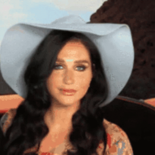A Woman Wearing A Cowboy Hat Is Looking At Something GIF