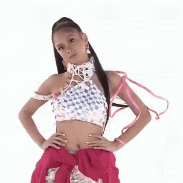A Woman Wearing A Crop Top And A Pink Skirt Is Standing With Her Hands On Her Hips . GIF