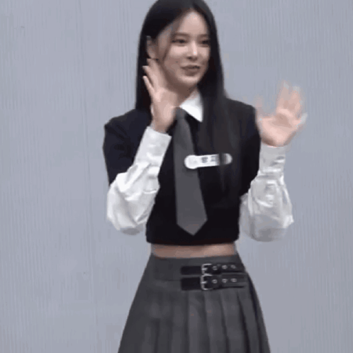 A Woman Wearing A Crop Top And Tie Is Waving Her Hands GIF
