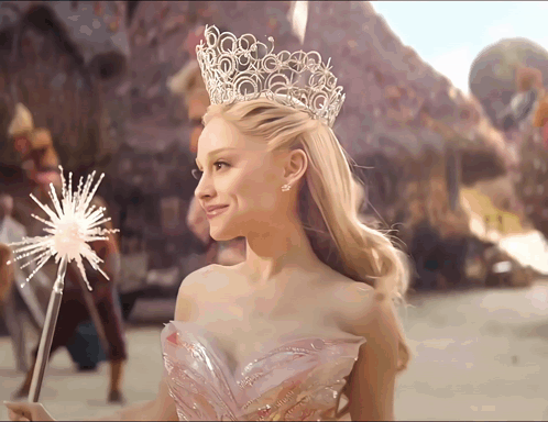 A Woman Wearing A Crown And A Pink Dress Holds A Sparkler GIF