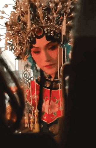 A Woman Wearing A Crown And A Red Dress Looks At Herself In A Mirror GIF