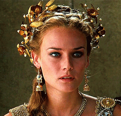 A Woman Wearing A Crown Of Gold Flowers And Earrings GIF