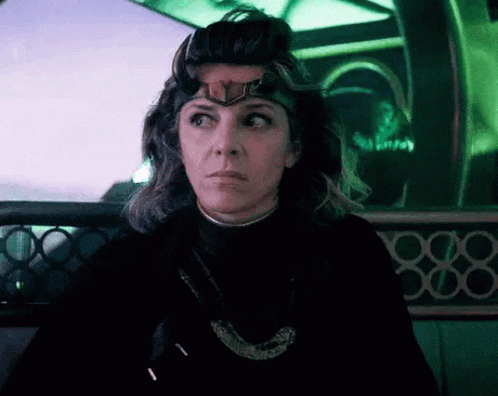 A Woman Wearing A Crown On Her Head Is Sitting In A Dark Room . GIF
