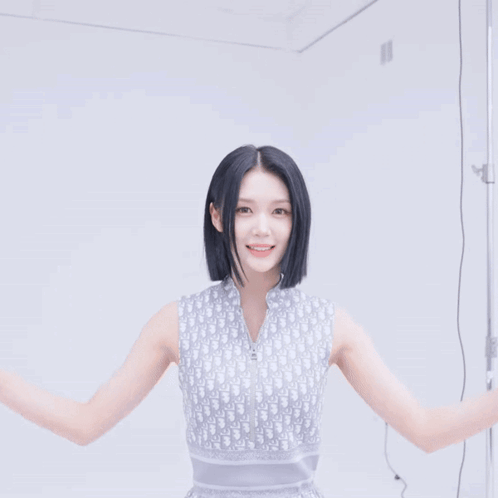 a woman wearing a dior sleeveless top smiles with her hands in the air