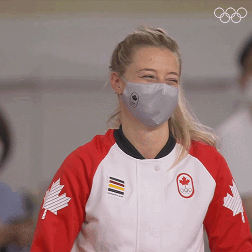 A Woman Wearing A Face Mask And A Jacket With A Canadian Maple Leaf On The Sleeves GIF
