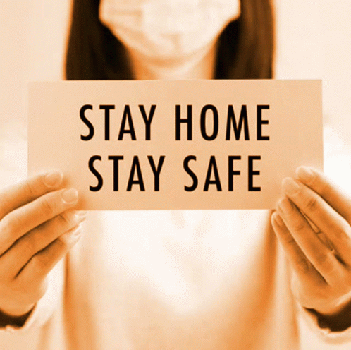 A Woman Wearing A Face Mask Is Holding A Sign That Says Stay Home Stay Safe GIF