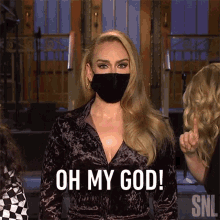 A Woman Wearing A Face Mask Is Standing In Front Of A Group Of People . GIF