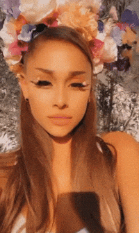 A Woman Wearing A Flower Crown Looks At The Camera GIF