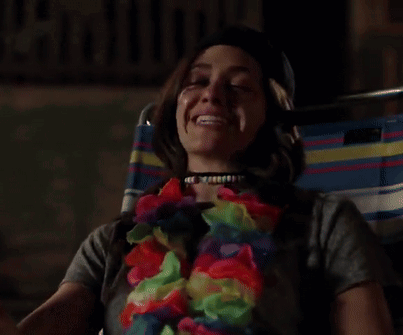 A Woman Wearing A Flower Lei And A Choker Is Laughing GIF