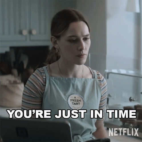 a woman wearing a fresh tart apron is sitting in front of a laptop and says you 're just in time