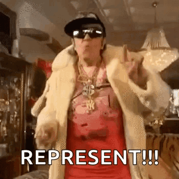 a woman wearing a fur coat , sunglasses , a hat and a dollar sign necklace is dancing .