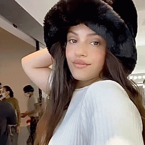 A Woman Wearing A Fur Hat And A White Shirt GIF