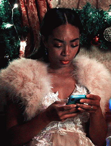 A Woman Wearing A Fur Stole Is Looking At Her Cell Phone GIF