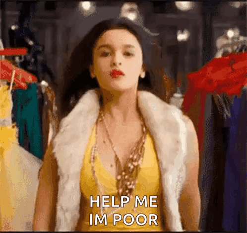 A Woman Wearing A Fur Vest And A Yellow Top Is Standing In Front Of A Clothes Rack And Asking For Help . GIF