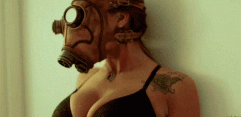 A Woman Wearing A Gas Mask With A Tattoo On Her Arm . GIF