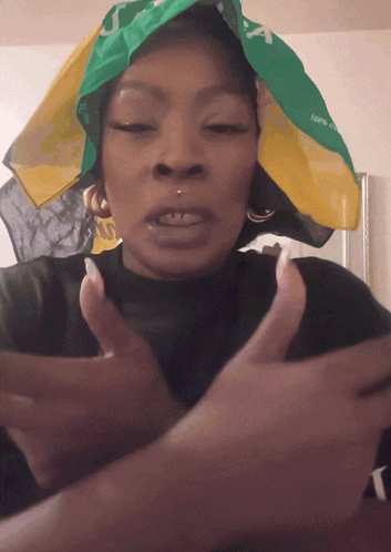 A Woman Wearing A Green And Yellow Bandana That Says Jamaica GIF