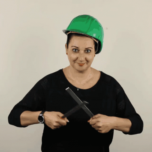 A Woman Wearing A Green Hard Hat Is Holding A Pair Of Scissors In Her Hands GIF