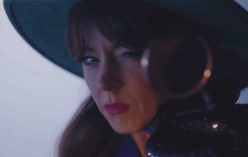 A Woman Wearing A Green Hat And Magnifying Glass GIF