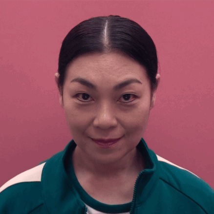 A Woman Wearing A Green Jacket Is Smiling And Looking At The Camera GIF