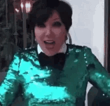 A Woman Wearing A Green Sequined Top And A Bow Tie Is Laughing . GIF