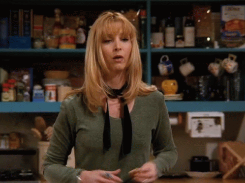 A Woman Wearing A Green Shirt And A Black Tie Is Standing In Front Of A Shelf Full Of Food GIF