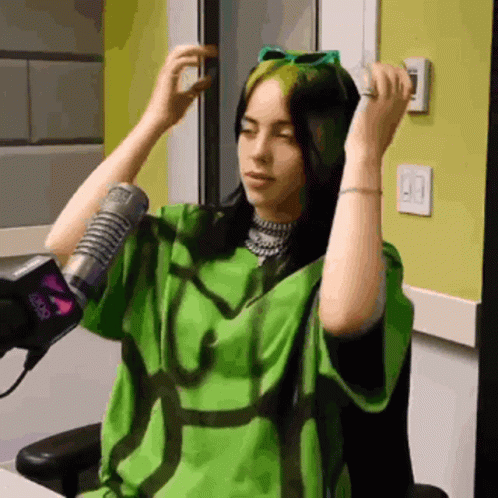 A Woman Wearing A Green Shirt Is Sitting In Front Of A Microphone GIF