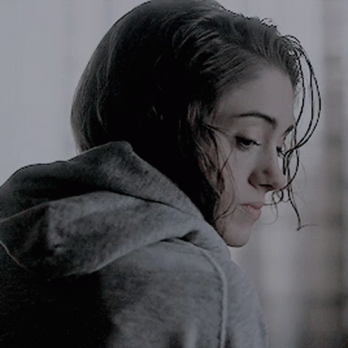 A Woman Wearing A Grey Hoodie Is Looking Down At Something GIF