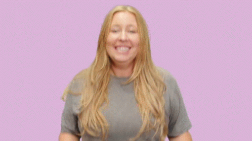 A Woman Wearing A Grey T-Shirt Is Smiling With Her Hands Outstretched GIF