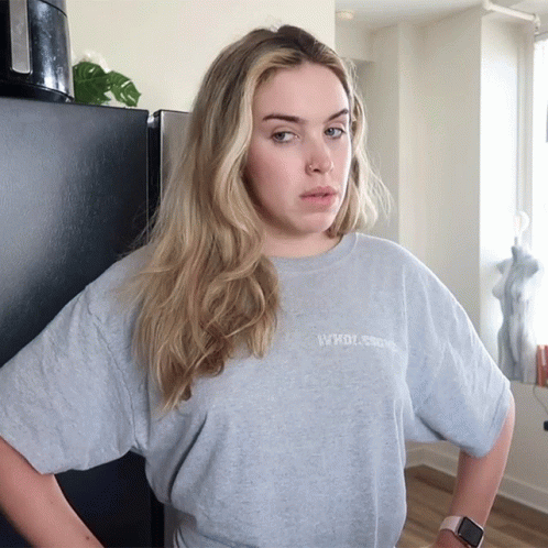 A Woman Wearing A Grey T-Shirt That Says " Who Cares " Stands With Her Hands On Her Hips GIF